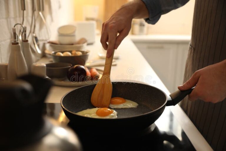 hombre cocinando huevos en la cocina